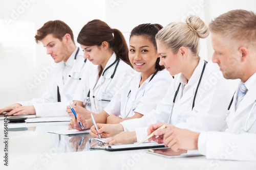 Row Of Doctors Writing At Desk