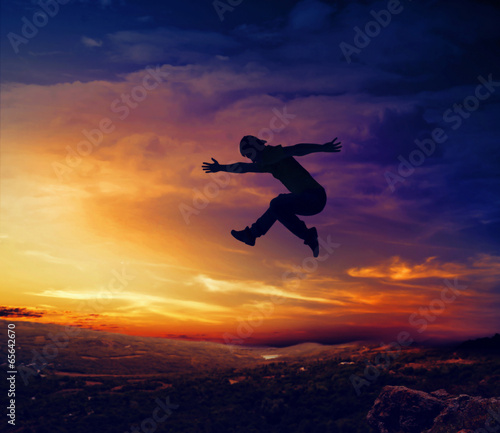 Silhouette of man jumping off a cliff