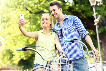 Happy couple taking pictures of themselves on a bike