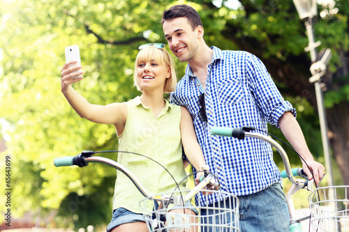 Happy couple taking pictures of themselves on a bike photo