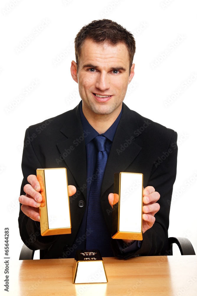 Handsome businessman in suit holds two gold brick Handsome businessman in suit holds two gold brick