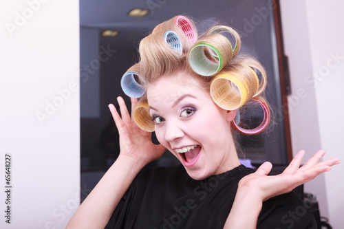 Cheerful funny blond girl hair curlers rollers by haidresser photo