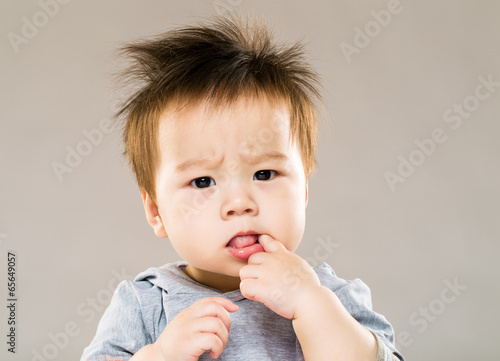 Little boy put finger into mouth photo