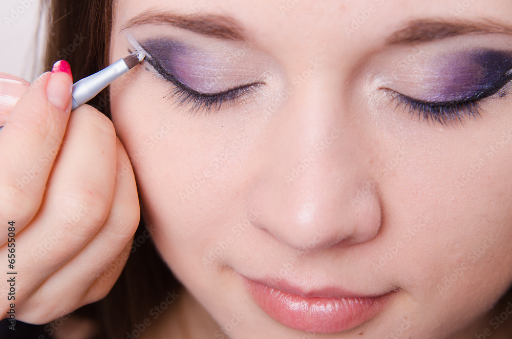 Pretty girl makeup artist draws arrows on eyes