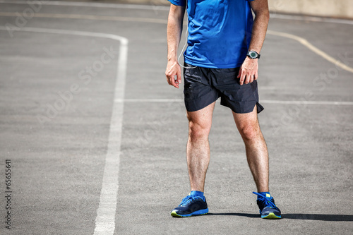 Male runner standing on racing track after workout.