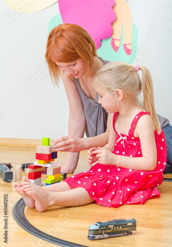 Little girl and her mother playing with railway photo