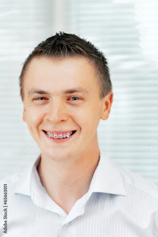 Smiling young man with orthodontic braces.