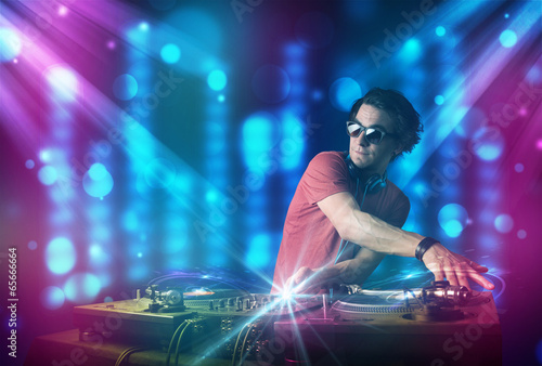 Dj mixing music in a club with blue and purple lights © ra2 studio