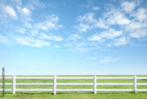white fence on green grass with blue sky