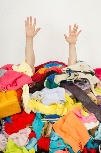 Man hands reaching out for help from a big pile of woman clothes photo
