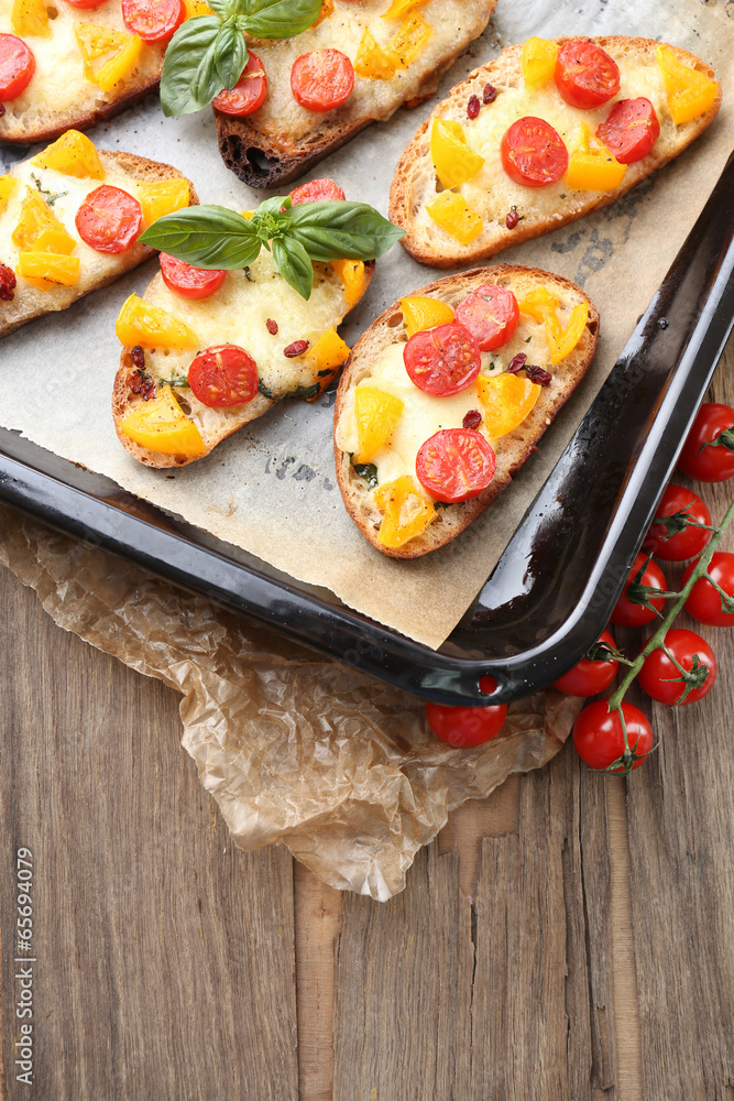 Tasty bruschetta with tomatoes on pan, on old wooden table Tasty bruschetta with tomatoes on pan, on old wooden table