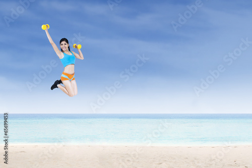 Cheerful sporty woman holding dumbbells