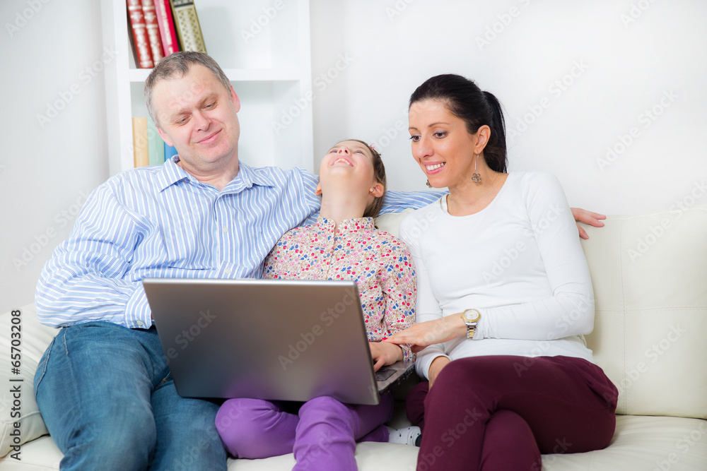 Fototapeta premium Family sitting on the sofa and looking at laptop