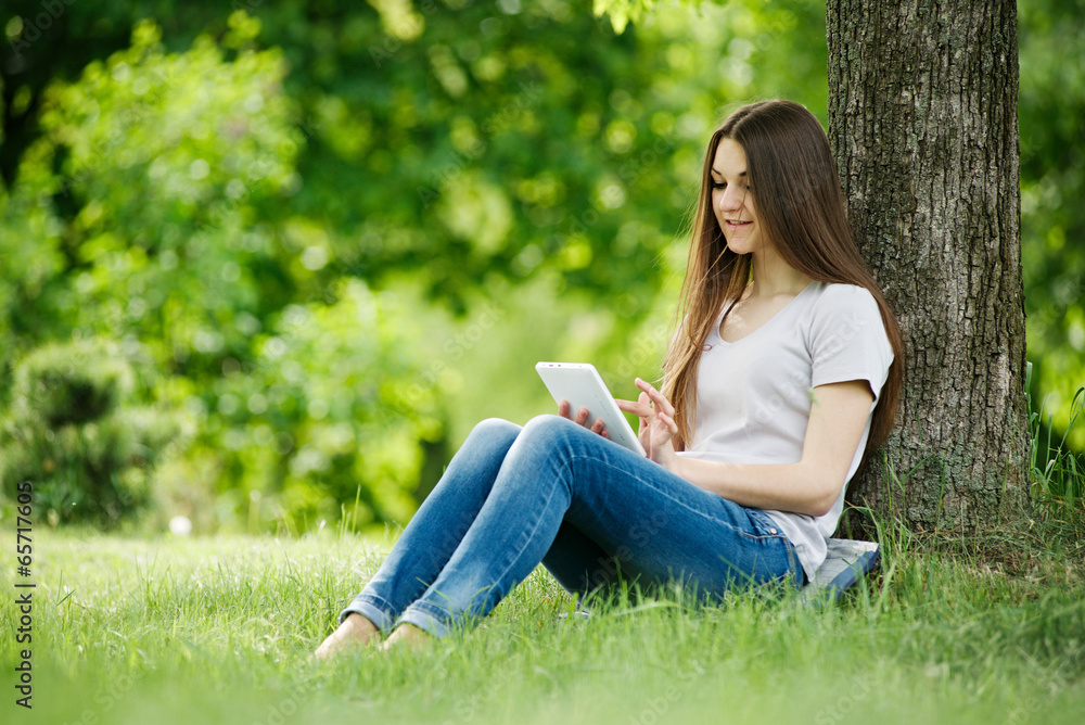 Young girl relaxing with her tablet in a park