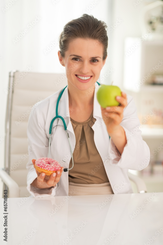 Happy medical doctor woman giving apple instead of donut Happy medical doctor woman giving apple instead of donut