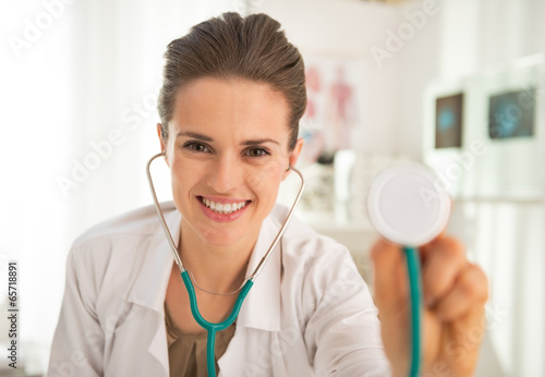 Happy medical doctor woman stretching stethoscope in camera
