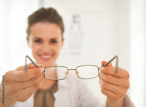 Closeup on ophthalmologist doctor woman giving eyeglasses