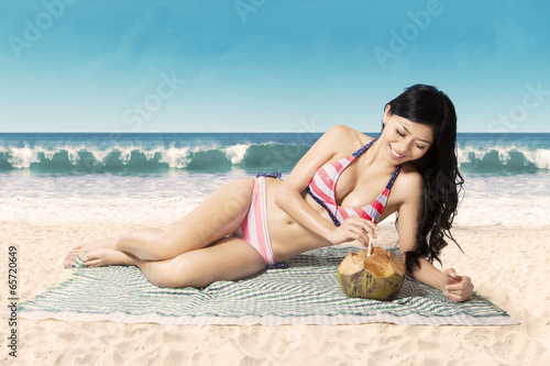 Smiling woman drinking coconut water