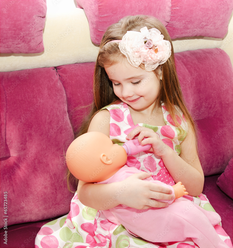 Cute smiling little girl playing with a doll Stock Photo | Adobe Stock