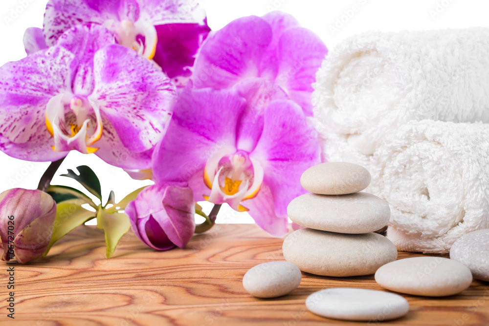 Spa setting with stones, lilac orchids and towels is isolated on Spa setting with stones, lilac orchids and towels is isolated on