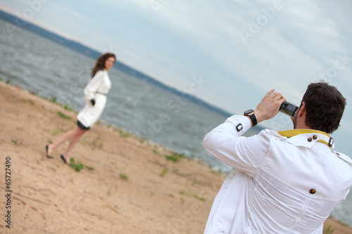 Man photographing woman on phone in cloudy weather.