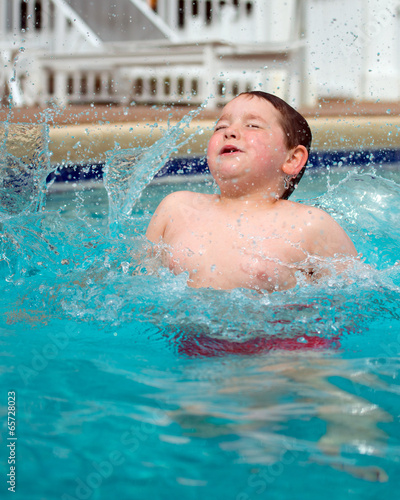Young boy splashing into pool while swimming © Robert Hainer