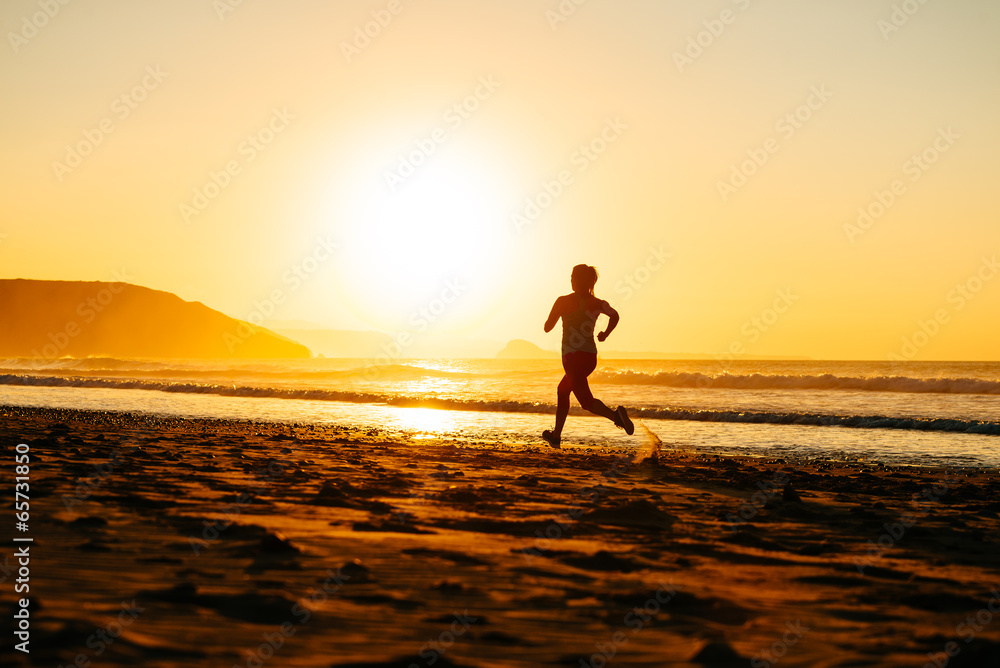 Female athlete running on sunset at beach