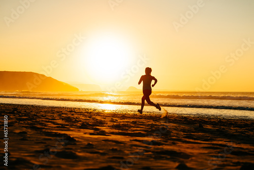 Female athlete running on sunset at beach
