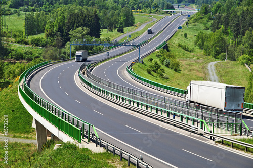 Obraz na płótnie The highway between woods, electronic toll gates, moving trucks w salonie