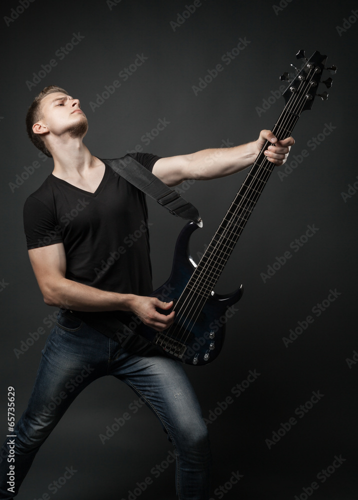 young male musician playing a six-string bass guitar isolated on young male musician playing a six-string bass guitar isolated on