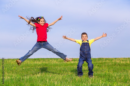 Jumping kids on green field