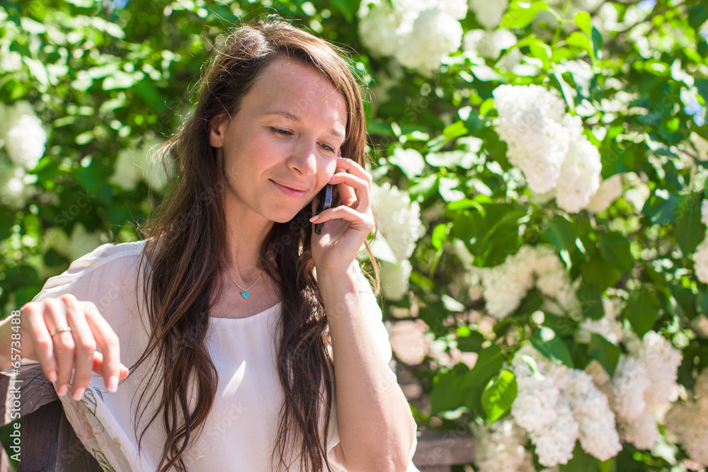 Young woman talking on her phone at flower garden Young woman talking on her phone at flower garden