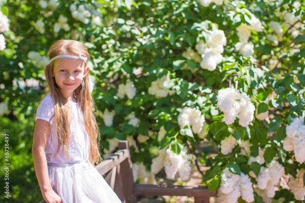 Adorable happy little girl have fun in flower blossoming garden
