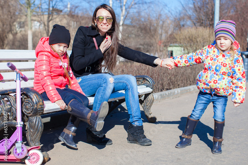 Happy mother and little girls enjoy sunny day in the park