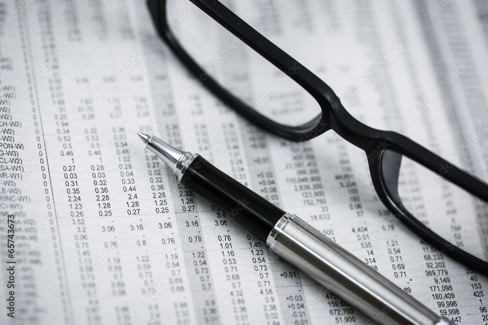 closeup glasses on financial newspaper with pen closeup glasses on financial newspaper with pen