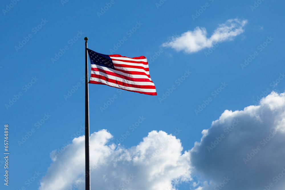 American flag - star and stripes floating over a cloudy blue sky American flag - star and stripes floating over a cloudy blue sky
