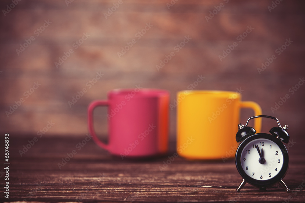 Two tea cup and alarm clock on wooden table. Two tea cup and alarm clock on wooden table.