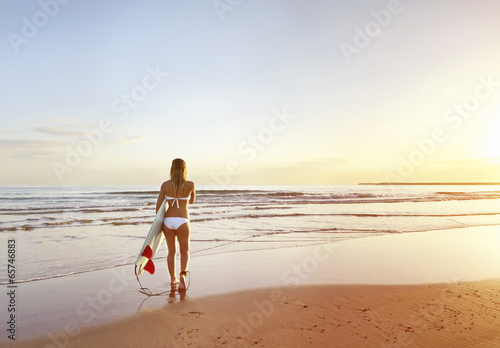 Young attractive surfer at the beach with surfboard