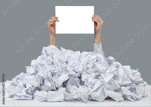 Hands reaches out from big heap of crumpled papers photo