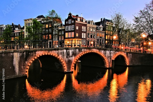 Canal houses of Amsterdam with bridge lit at night, Netherlands