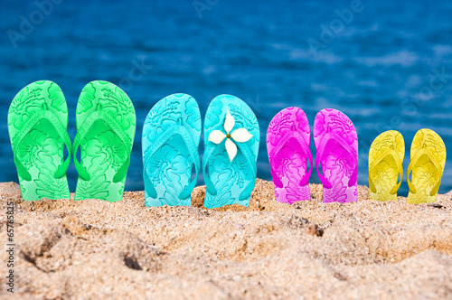 Flip flops of a family of four in the sand of a beach