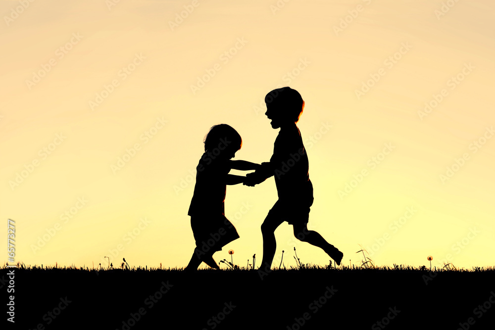 Silhouette of Happy Little Children Dancing at Sunset