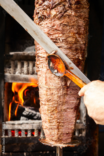 Doner meat being sliced from rotating spit photo