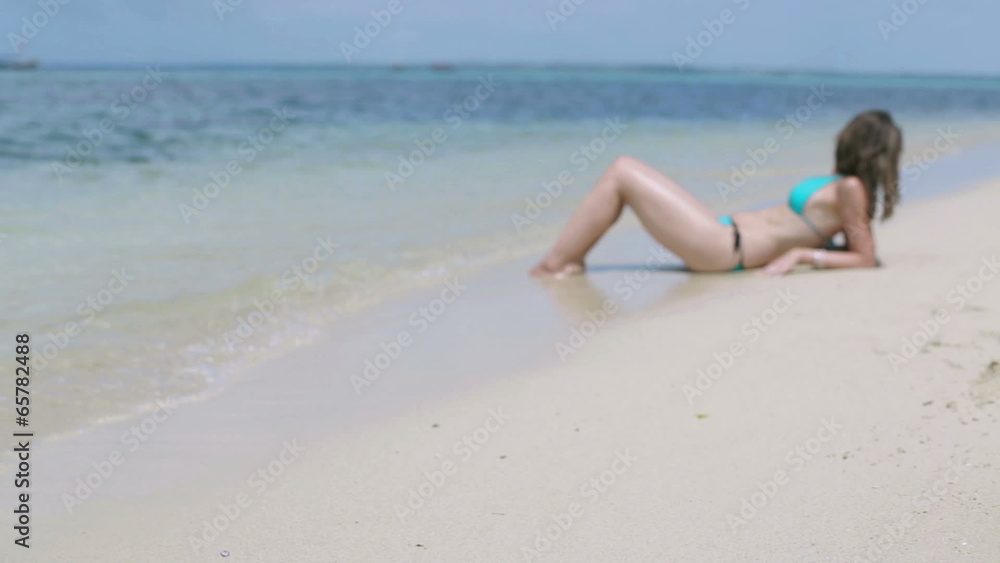 Luggage lying on the beach and woman resting in background, stea Luggage lying on the beach and woman resting in background, stea