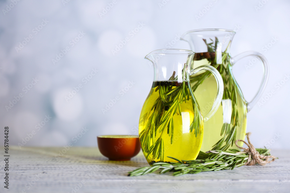 Essential Oil with rosemary in glass jug, on light background