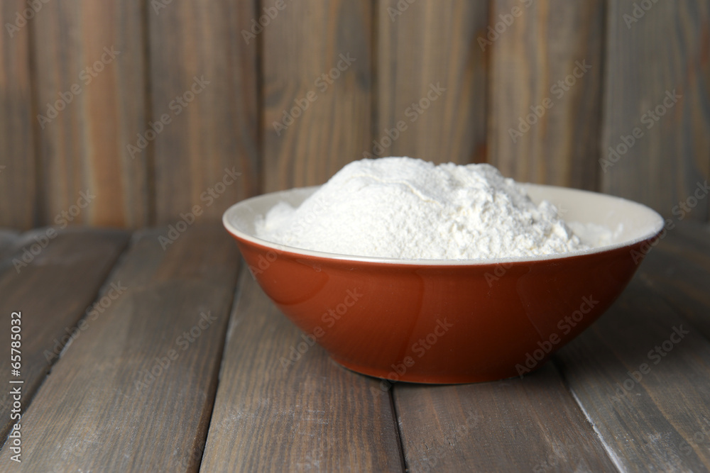Flour in bowl on table on wooden background Flour in bowl on table on wooden background