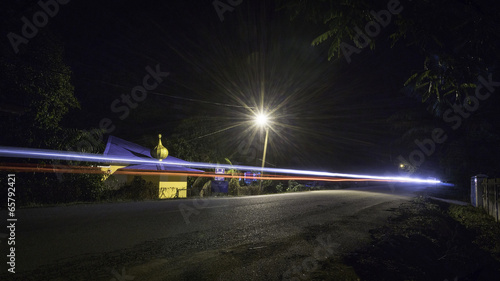 Road at night with car light trail in rural Malaysia