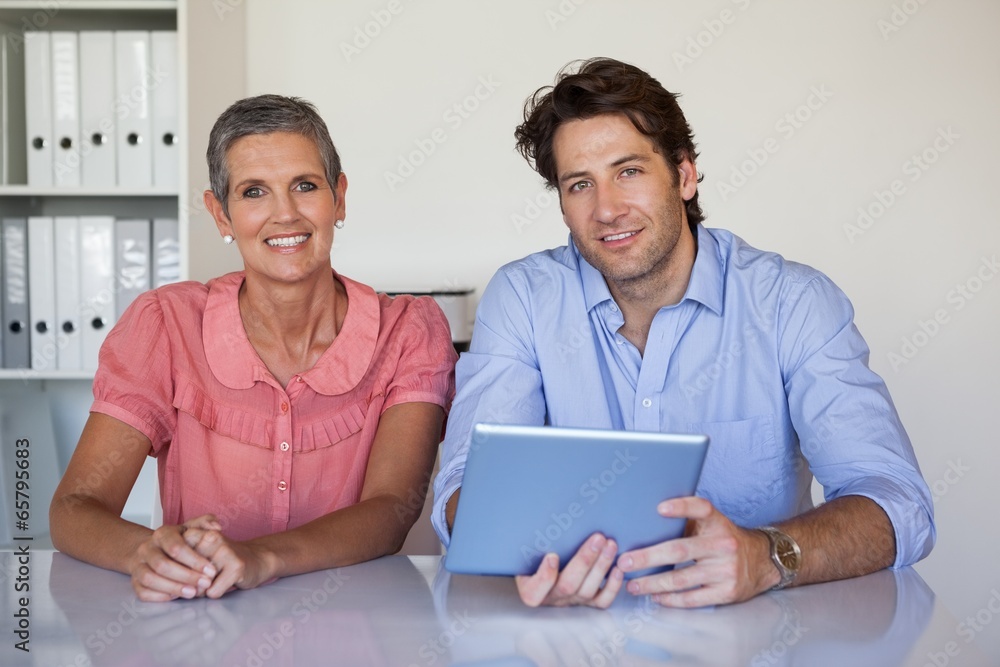 Casual smiling business team working at desk using tablet Casual smiling business team working at desk using tablet