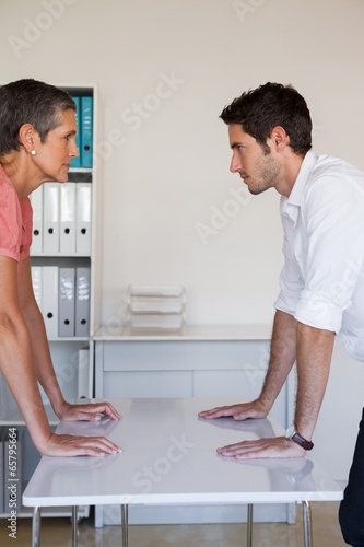 Casual business team arm wrestling at desk