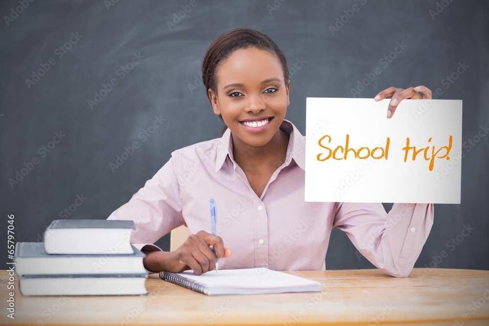Happy teacher holding page showing school trip Happy teacher holding page showing school trip